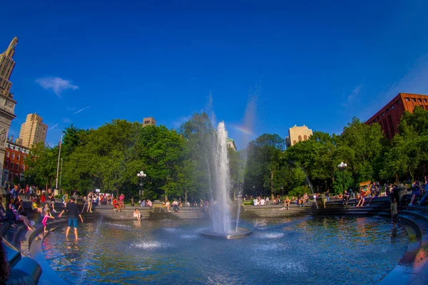 NEW YORK - JULY 22, 2017: Unidentified people enjoying the summer day in the Washington Square Park, inside of the fountain, with a small rainbow in the middle of the fountain in New York, fish eye — Stock Photo, Image