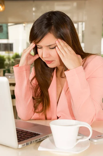Nahaufnahme einer im Büro gestressten jungen Geschäftsfrau, die ihren Kopf mit beiden Händen berührt und Kopfschmerzen hat. Geschäftskonzept — Stockfoto