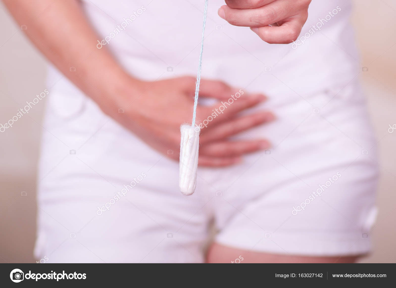 Young woman holding a menstruation cotton tampon with her hand and putting  in front of her white short Stock Photo by ©pxhidalgo 163027142