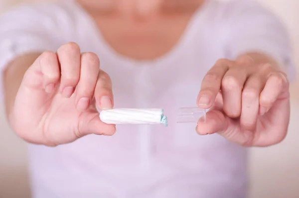 Close up de uma jovem apontando na frente dela um tampão de algodão menstruação em um fundo embaçado — Fotografia de Stock