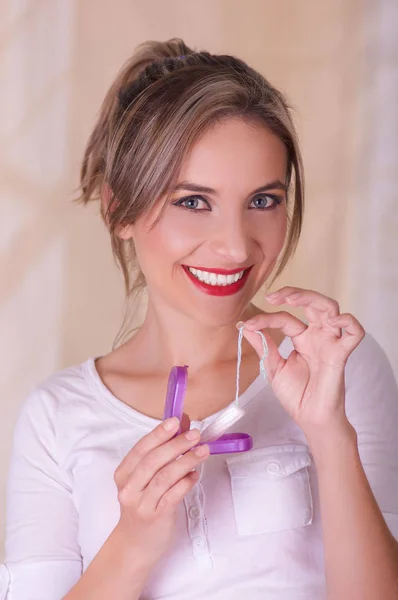 Joven hermosa mujer sonriente sosteniendo un tampón de algodón menstruación en una mano y con su otra mano una caja de plástico púrpura —  Fotos de Stock