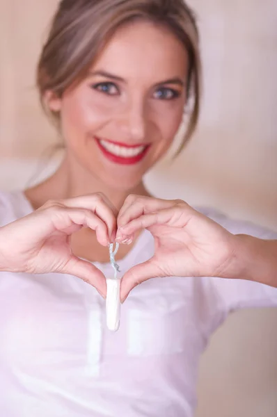 Jonge sexy mooie vrouw houden een menstruatie katoen tampon met beide handen en een hart doen ondertekenen met haar handen wijzen voor haar — Stockfoto