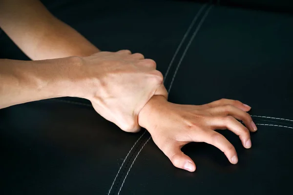 Close up mans hand holding a woman wrist over a black coach for rape and sexual abuse concept — Stock Photo, Image