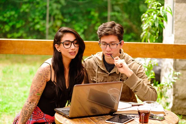 Coppia di hipster pensare e lavorare nel loro computer sul portico della casa di legno, estate rilassante insieme concetto, in uno sfondo cortile — Foto Stock