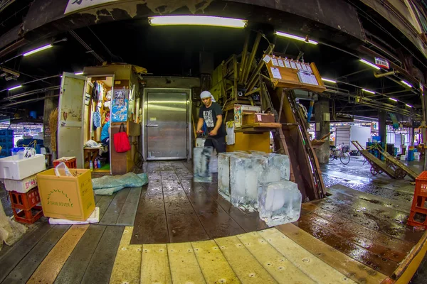 TOKYO, GIAPPONE 28 GIUGNO 2017: Uomo forte non identificato con un oggetto metallico in mano che si prepara a tenere un enorme pezzo di ghiaccio in un mercato di pesce Tsukiji è il più grande mercato all'ingrosso di pesce e frutti di mare — Foto Stock