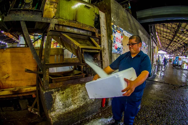 TOKIO, JAPÓN 28 DE JUNIO - 2017: Hombre fuerte no identificado sosteniendo en su mano una caja llena de hielo en un mercado de mariscos y pescados Tsukiji es el mercado mayorista de pescados y mariscos más grande del mundo, en — Foto de Stock