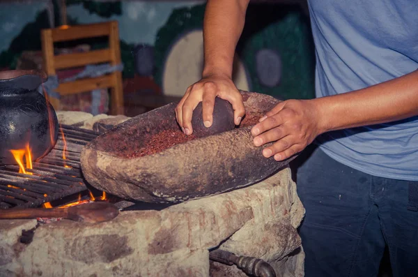 Mensen een cacao bonen malen over een rots, naast een houtkachel — Stockfoto