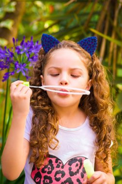 Mavi kulakları kaplan Aksesuar bulanık doğa arka planda onun Merkez over sabun köpüğü bir yaz niteliğine oynamaktan mutlu küçük kıvırcık kız giyiyor