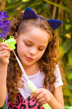 Mavi kulakları kaplan Aksesuar bulanık doğa arka planda onun Merkez over sabun köpüğü bir yaz niteliğine oynamaktan mutlu küçük kıvırcık kız giyiyor