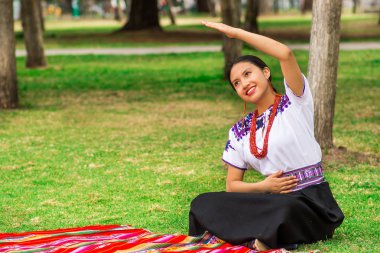 Quito, Ekvator - Ağustos, 30 2017: parkta egzersiz yaparak yere oturuyor ve tipik bir andean elbiseler giymiş belirsiz genç yerli kadın