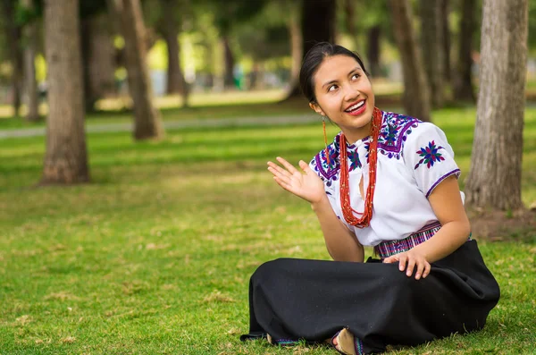 КИТО, ЕКУАДОР - 30 АВГУСТА 2017: Неопознанная молодая коренная женщина, одетая в типичную андскую одежду, сидит в земле в парке — стоковое фото
