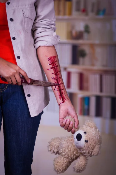 Öte yandan, arka plan bulanık de kanama, bir oyuncak ayı ve onu bir bıçak onun elinde tutan kolu ile bir genç depresif kadın kapat