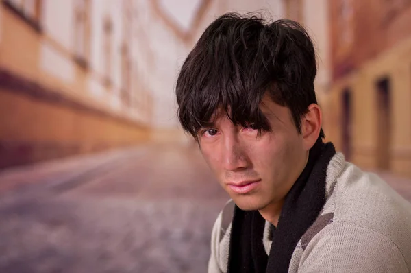 Portrait of a homeless young man in the streets, in a blurred background — Stock Photo, Image