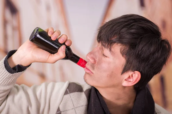 Portrait d'un jeune sans-abri dans la rue, buvant une bouteille de vin, dans un fond flou — Photo