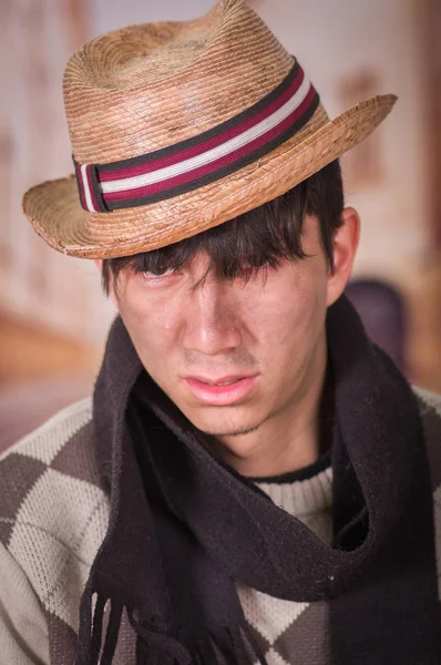 Крупним планом сумний безпритульний молодий чоловік на вулицях, одягнений в капелюх і шарф, на розмитому тлі — стокове фото
