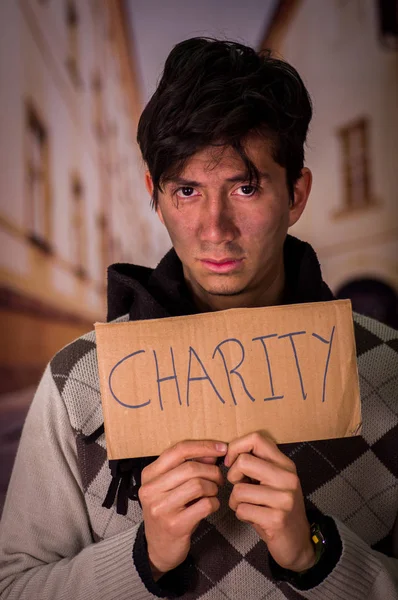 Detailní záběr z bezdomovce s karton popis charity, rozostřené pozadí — Stock fotografie