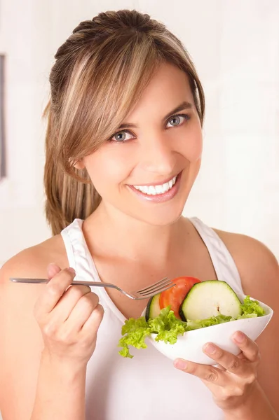 Belle jeune femme portant un t-shirt blanc et tenant dans sa main une salade saine — Photo