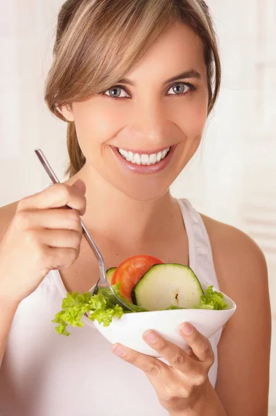 Beautiful young woman wearing a white t-shirt and holding in her hand a healthy salad — Stock Photo, Image