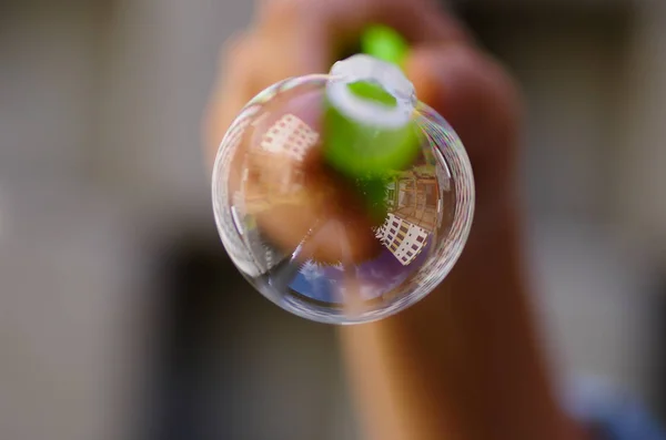 Primer plano de una burbuja de jabón sobre un fondo borroso, con un reflejo del edificio en la burbuja — Foto de Stock