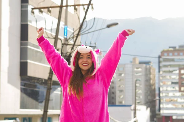Крупным планом красивая улыбающаяся молодая женщина в розовом костюме единорога, с обеими руками на открытом воздухе в городе Кито — стоковое фото