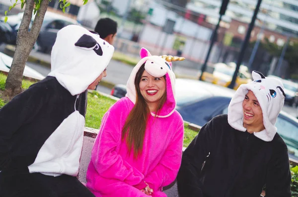 Close up de um grupo feliz de amigos tendo uma conversa divertida e vestindo trajes diferentes, uma mulher vestindo um traje de unicórnio rosa, outra mulher um traje de panda e o homem vestindo um traje de gato — Fotografia de Stock