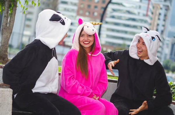 Primer plano de un grupo feliz de amigos teniendo una conversación divertida y usando diferentes disfraces, una mujer usando un traje de unicornio rosa, otra mujer un disfraz de panda y el hombre usando un disfraz de gato — Foto de Stock