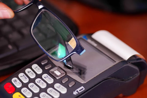 Pagamento moderno com nova tecnologia de pagamentos usando óculos inteligentes com chip, comprar e vender serviços de produtos em uma mesa de madeira — Fotografia de Stock