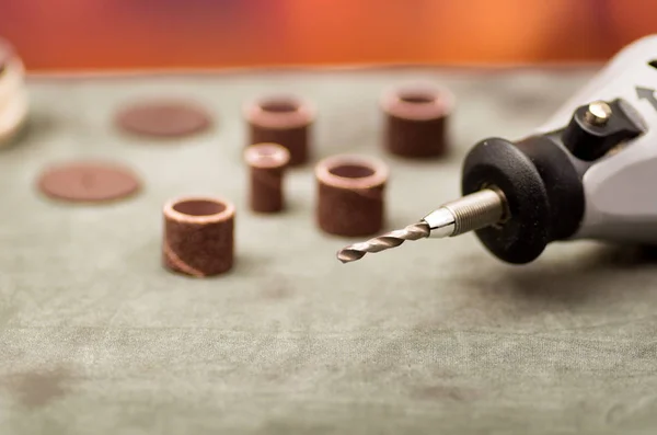 Close up of selective focus of a gray drill with drilling accessories on gray table in a blurred background — Stock Photo, Image