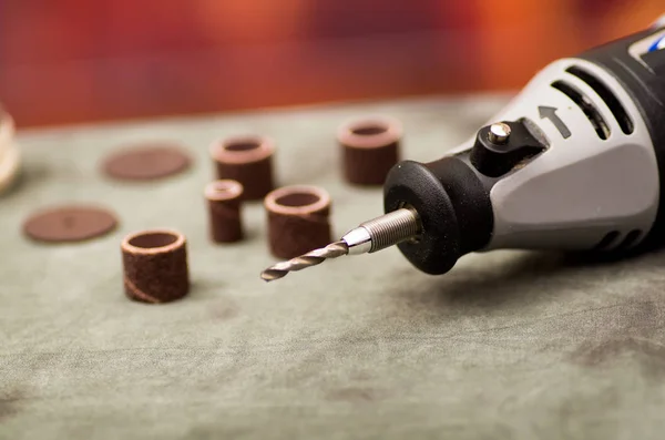 Primo piano di un trapano con accessori di perforazione su tavolo grigio in uno sfondo sfocato — Foto Stock