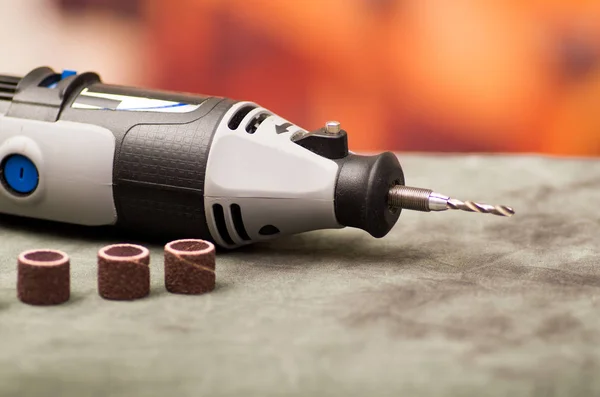 Close up of a drill with drilling accessories on gray table in a blurred background — Stock Photo, Image