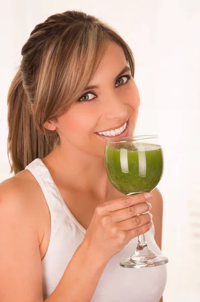 Hermosa joven sonriente con una camiseta blanca y sosteniendo una ensalada saludable con una mano y un vaso de jugo en la otra mano — Foto de Stock