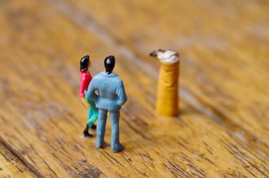 Minyatür küçük insanların çifte bir sigara seyir açık havada, popo, ahşap arka planda