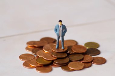 Minyatür küçük insanlar, adam beyaz bir arka plan bir sent yığını üzerinde poz