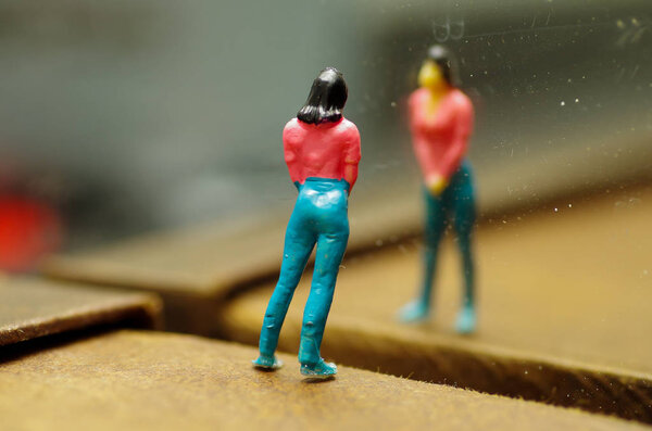 Миниатюрные маленькие люди, женщина, смотрящая на Герслефа в зеркале, на размытом фоне
