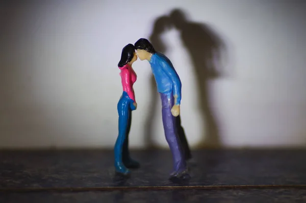 Pequenas pessoas miniatura, casal beijando com uma sombra atrás — Fotografia de Stock