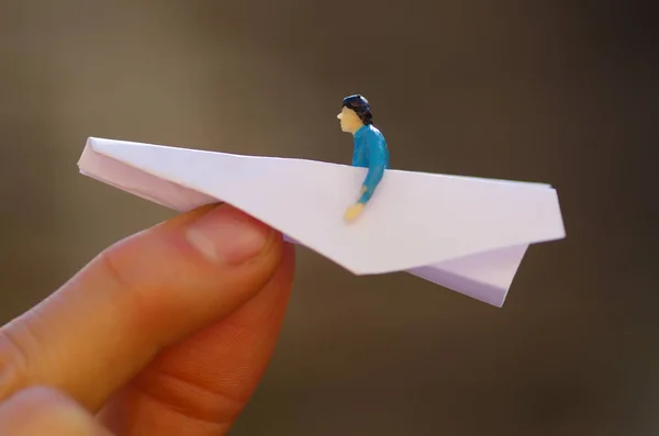 Miniature little people, man inside of a paper airplane in a blurred background — Stock Photo, Image
