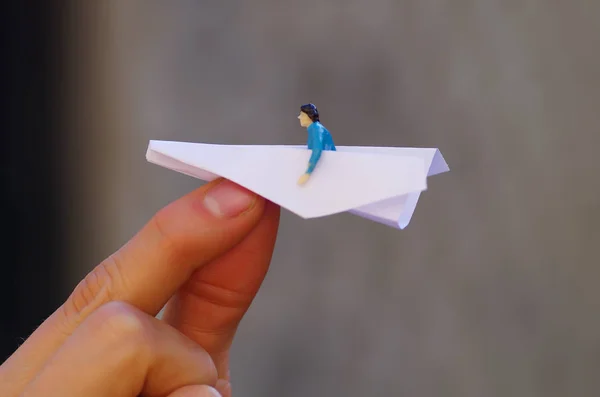 Pequenas pessoas em miniatura, homem dentro de um avião de papel em um fundo turvo — Fotografia de Stock