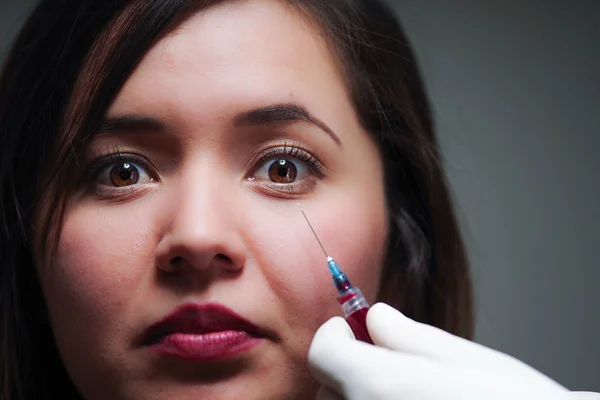 Retrato de una mujer hermosa y aterradora, con un tratamiento de inyección de aguja cerca de su cara —  Fotos de Stock