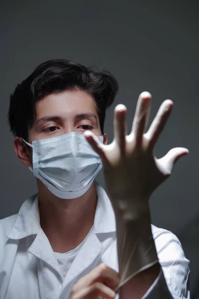 Zbliżenie lekarza z szczęśliwy twarz na sobie biały chirurgiczne maskować ciemnym tle ina — Zdjęcie stockowe
