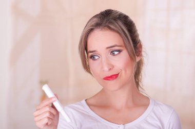 Bir adet pamuk tampon arka plan bulanık elinde tutan endişeli bir yüz, genç güzel kadın