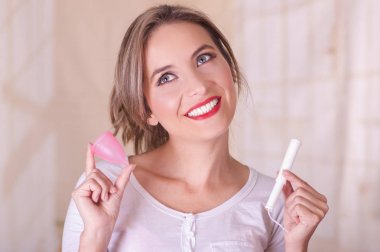 Arka plan bulanık bir adet kaba genç güzel gülümseyen kadın adet pamuk tampon bir elinde ve onunla birlikte diğer elini tutarak yakın çekim