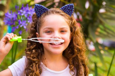 Mavi kulakları kaplan Aksesuar bulanık doğa arka planda onun Merkez over sabun köpüğü bir yaz niteliğine oynamaktan mutlu küçük kıvırcık gülümseyen kız giyiyor