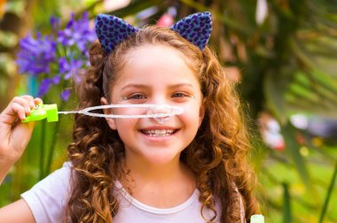 Mavi kulakları kaplan Aksesuar bulanık doğa arka planda onun Merkez over sabun köpüğü bir yaz niteliğine oynamaktan mutlu küçük kıvırcık gülümseyen kız giyiyor