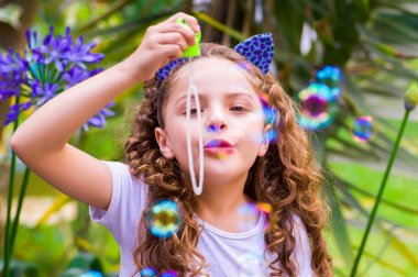 Mavi kulakları kaplan Aksesuar bulanık doğa arka planda onun Merkez over sabun köpüğü bir yaz niteliğine oynamaktan mutlu küçük kıvırcık kız giyiyor