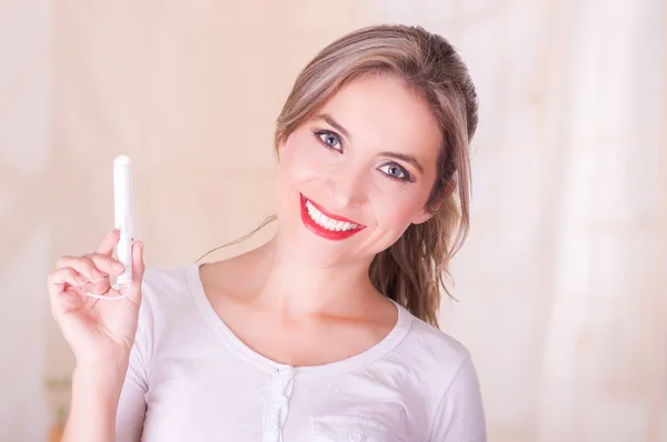 Jovem bela mulher sorridente segurando um tampão de algodão menstruação em sua mão — Fotografia de Stock