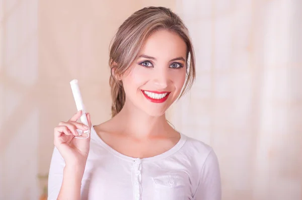 Young beautiful smiling woman holding a menstruation cotton tampon in her hand — Stock Photo, Image