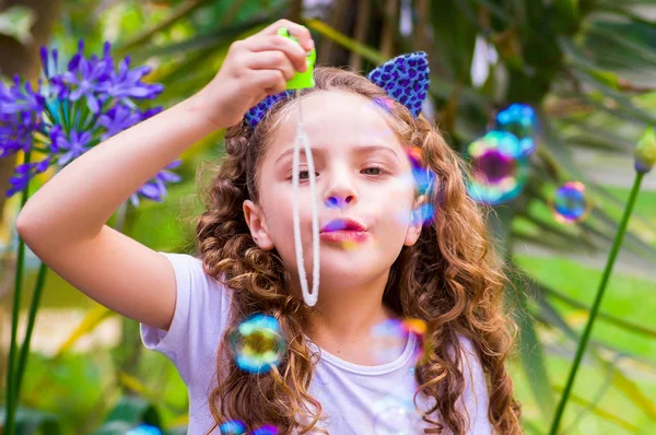 Mavi kulakları kaplan Aksesuar bulanık doğa arka planda onun Merkez over sabun köpüğü bir yaz niteliğine oynamaktan mutlu küçük kıvırcık kız giyiyor