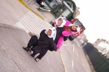 Mutlu bir grup arkadaşıyla, sokakta oynayan ve farklı Kostümler, pembe tek boynuzlu at kostüm giyen bir kadın, bir panda kostümü başka bir kadın ve bir kedi kostümü giyiyor adam, yakın çekim