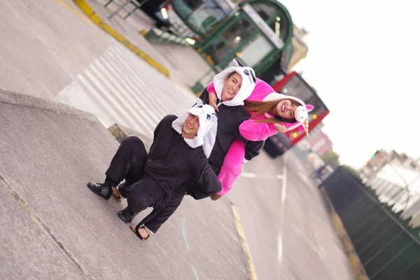 Nahaufnahme einer fröhlichen Gruppe von Freunden, die auf der Straße spielen und verschiedene Kostüme tragen, eine Frau trägt ein rosafarbenes Einhornkostüm, eine andere ein Panda-Kostüm und der Mann ein Katzenkostüm. — Stockfoto