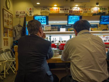 Tokyo, Japonya -28 Haziran 2017: kimliği belirsiz kişi bir kaitenzushi Konveyör bant suşi restoranı, Tokyo içinde bir tablo üzerinde bir çeşitli japanesse yemek yeme